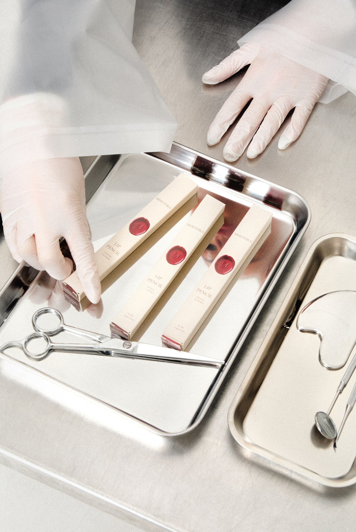 Gloved hands arranging lip pencils on a steel tray